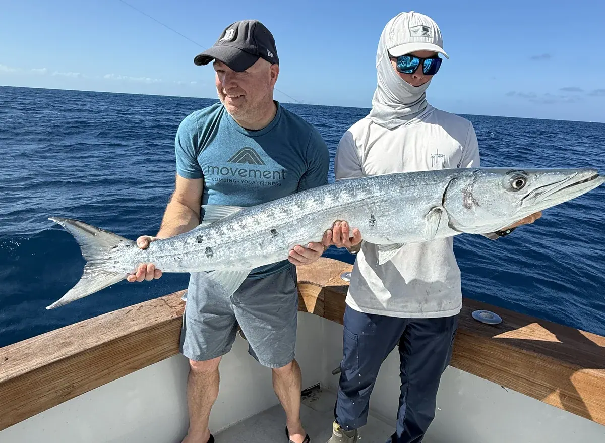 Two anglers holding a barracuda aboard the Double Threat off Miami