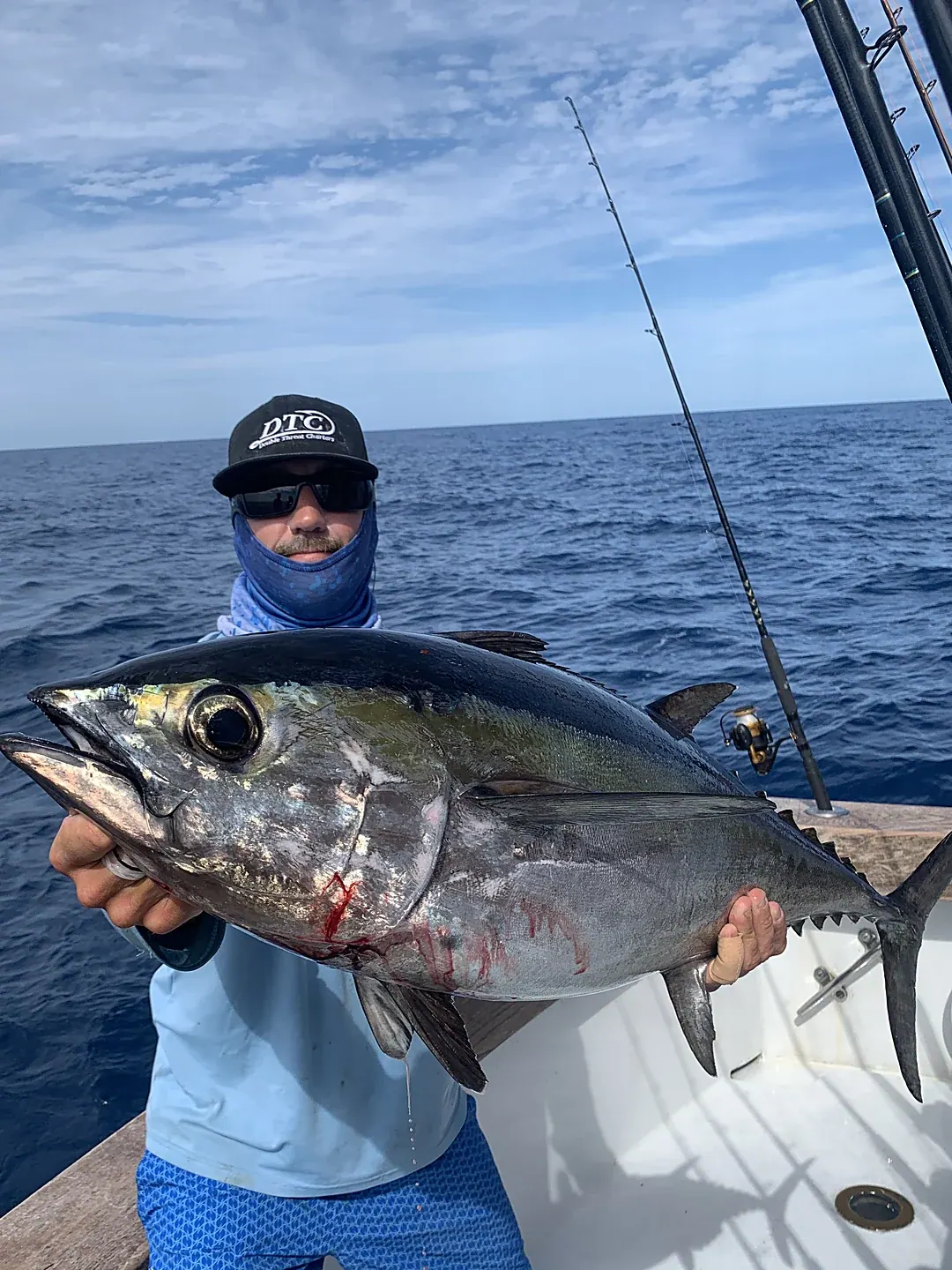 An angler holding a blackfin tuna boatside with the Miami skyline behind