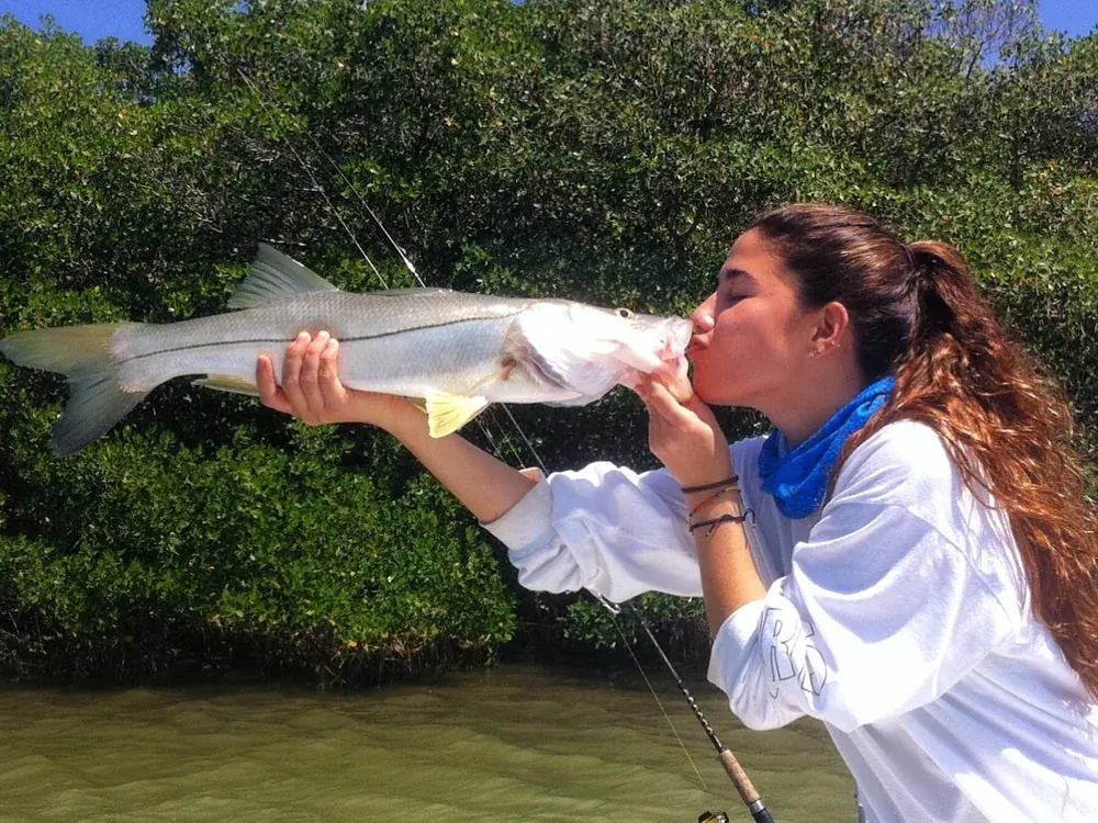 An angler kissing a snook caught on a Miami inshore fishing trip