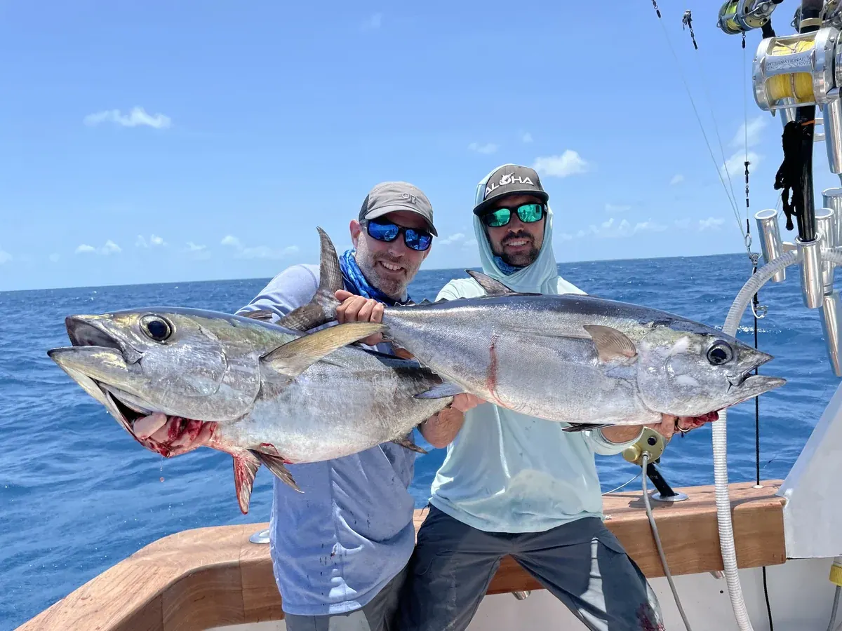 Two anglers on the deck of the Double Threat holding a pair of fish caught offshore Miami
