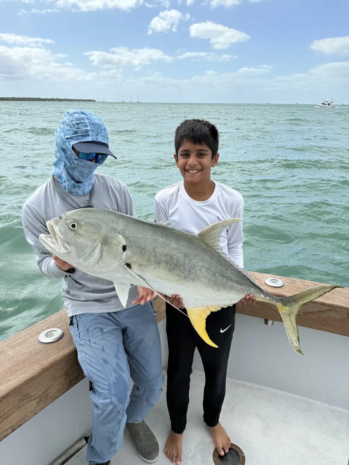 A young angler and his guide holding a jack crevalle at the boat off Miami