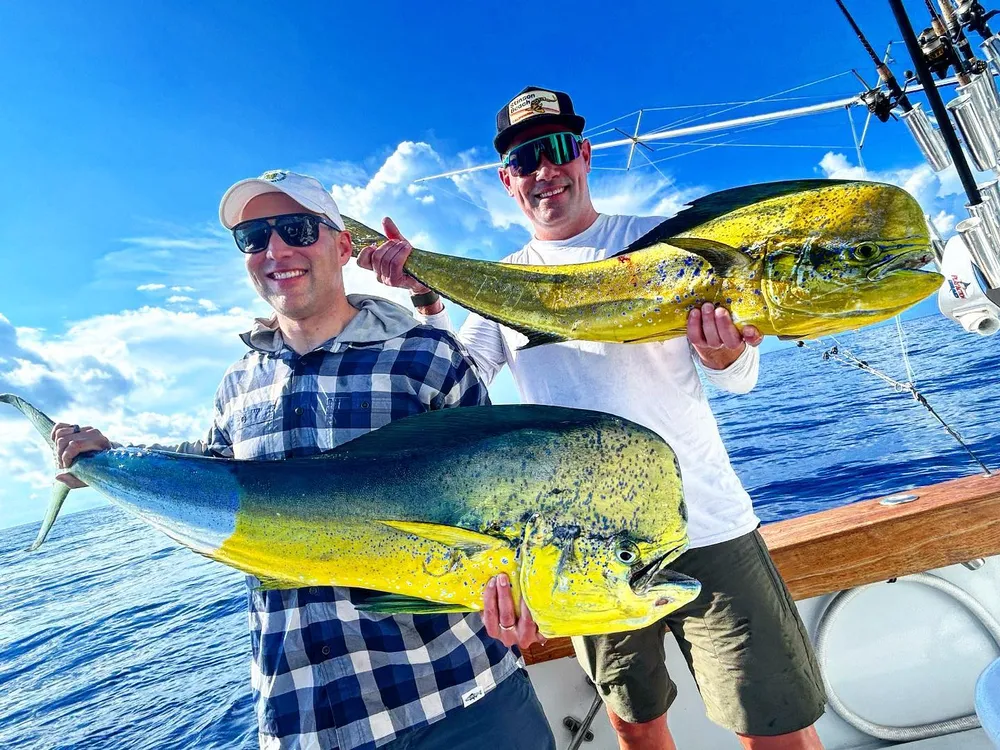 Two anglers holding up a pair of mahi-mahi caught offshore of Miami