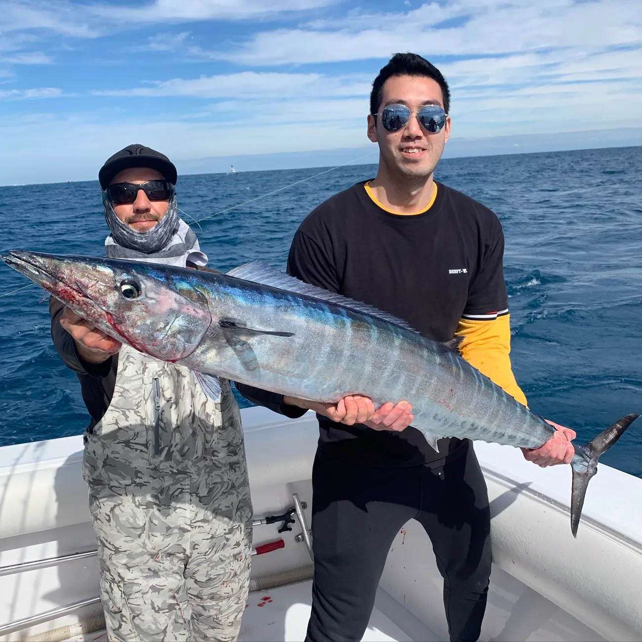 Two anglers holding a wahoo caught off Miami on a clear day