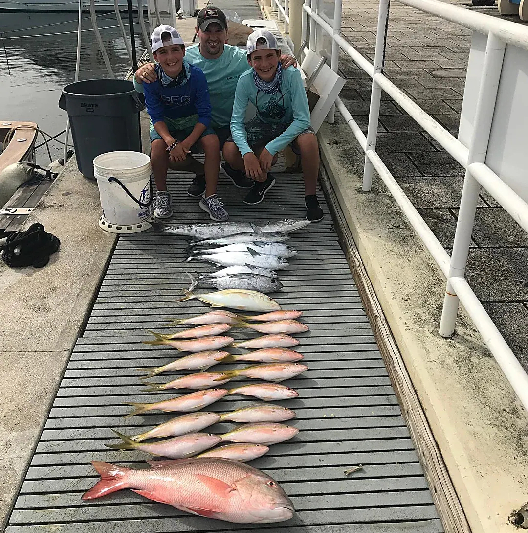 A family on the dock with their catch of yellowtail snapper and more after a Miami charter
